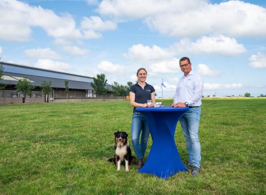 Melkveehoudster Anna Tjitske Wienia en DeLaval Solution Manager Sigmar Vosjan in een weiland aan een statafel met een glas melk. 